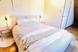 This cozy bedroom features a comfortable bed with a striped comforter and a soft blanket, perfect for a relaxing retreat.