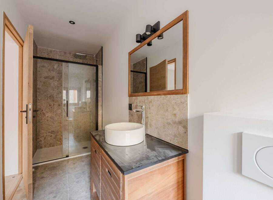 This modern bathroom features a sleek design with a wooden vanity and a stylish vessel sink.