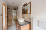 This modern bathroom features a sleek design with a wooden vanity and a stylish vessel sink.