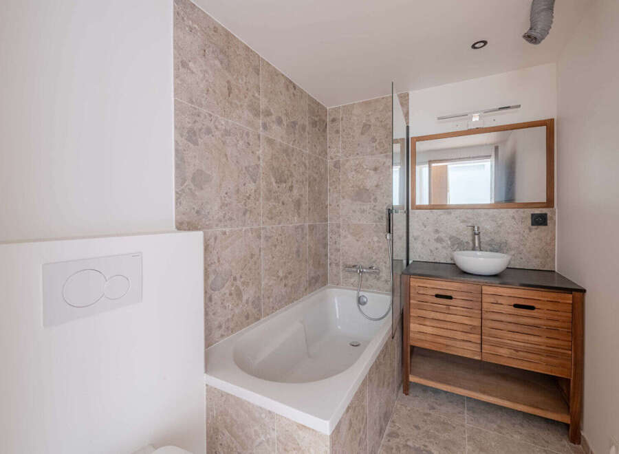 This modern bathroom features a sleek design with a bathtub and a stylish vanity.