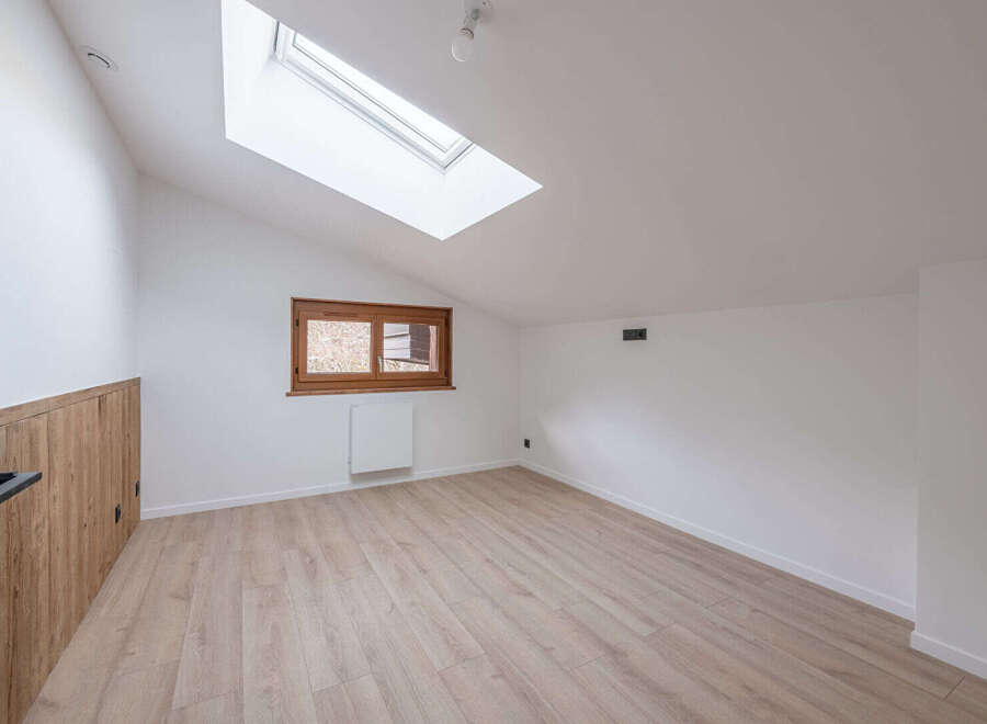 This bright and airy room features a modern design with a sloped ceiling and a skylight, creating a spacious feel.