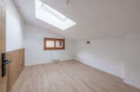 This bright and airy room features a modern design with a sloped ceiling and a skylight, creating a spacious feel.