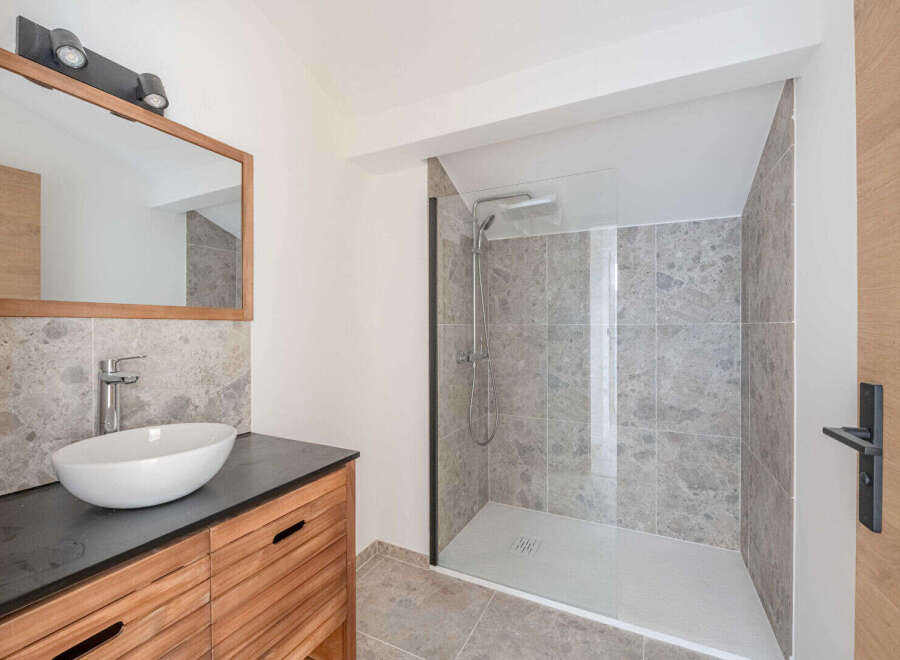 This modern bathroom features a sleek design with a spacious walk-in shower and a stylish vanity.