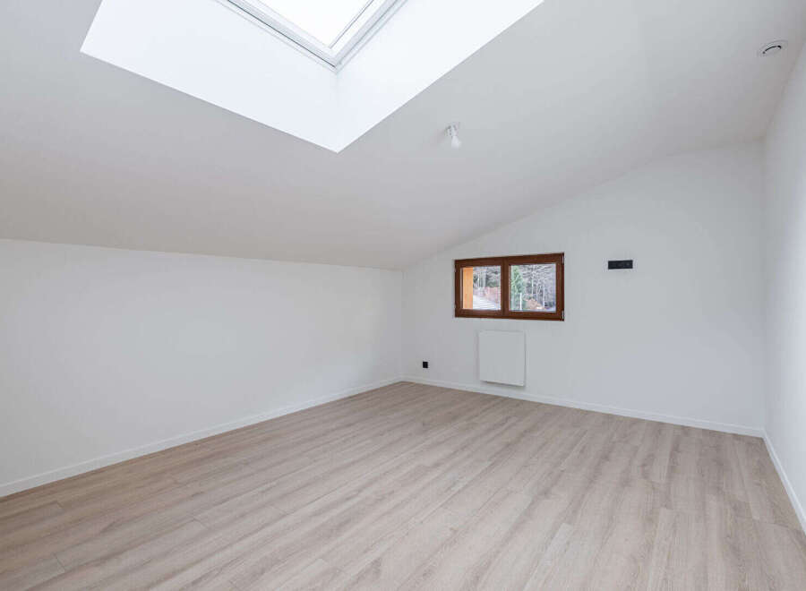 This bright and airy room features a modern design with a skylight and a window that offers natural light.