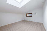 This bright and airy room features a modern design with a skylight and a window that offers natural light.