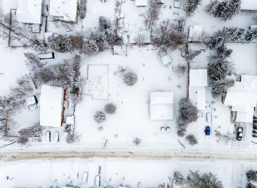 This aerial view showcases a snow-covered residential area, highlighting the winter landscape and property features.