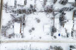 This aerial view showcases a snow-covered residential area, highlighting the winter landscape and property features.