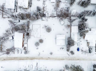 This aerial view showcases a snow-covered residential area, highlighting the winter landscape and property features.