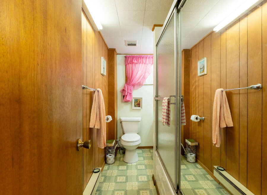 Step back in time with this charming bathroom! Featuring classic wood paneling, a vintage-style toilet, and a touch of retro flair, this space offers a unique aesthetic.