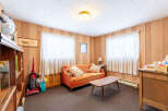 Step into this cozy living space, featuring warm wood paneling and ample natural light from the large windows.