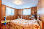 Step into this cozy bedroom featuring warm wood paneling and a charming ambiance.