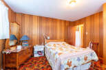 Step into this cozy bedroom featuring warm wood paneling and a charming vintage aesthetic.