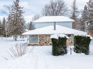 This charming property boasts a cozy exterior with a stone facade and a snow-covered roof, perfect for winter.