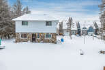 This charming property features a unique stone facade and a snow-covered roof, creating a cozy winter scene.