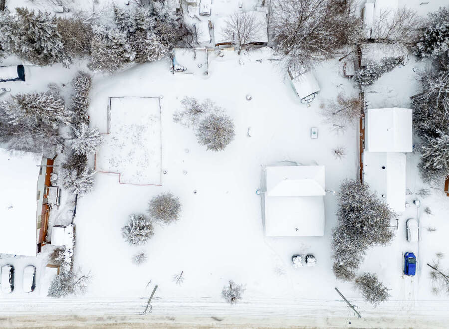 This aerial view showcases a snow-covered property, highlighting the winter landscape and the architectural details of the houses.
