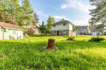 Discover this charming property featuring a unique two-story home with a stone foundation and siding, complemented by a detached green shed adorned with whimsical wolf cutouts.