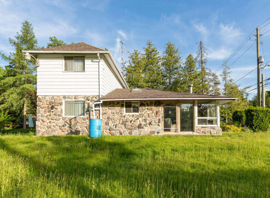Discover this charming property featuring a unique stone foundation and classic white siding, offering a blend of rustic and modern appeal.