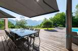 Enjoy outdoor living at its finest with this stunning property featuring a spacious wooden deck and a modern glass-top dining table, perfect for entertaining.