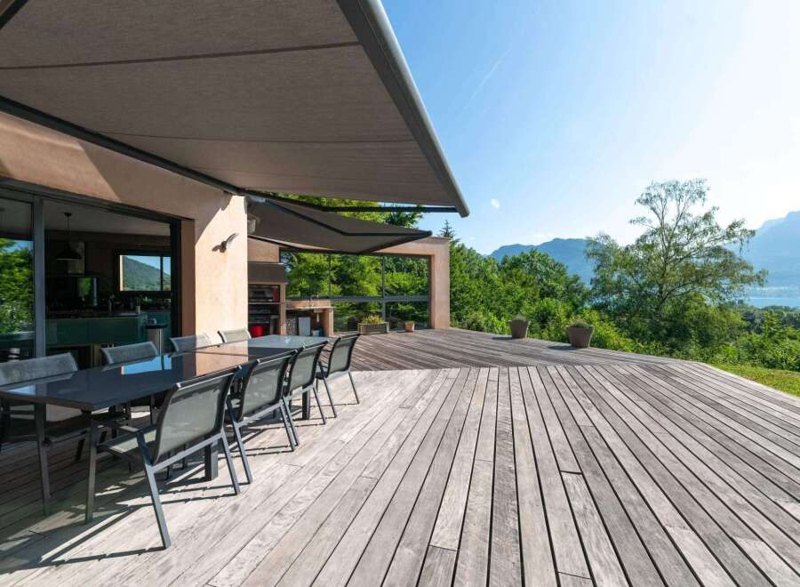 Enjoy outdoor living at its finest with this stunning property featuring a spacious wooden deck and a modern outdoor dining area.