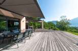 Enjoy outdoor living at its finest with this stunning property featuring a spacious wooden deck and a modern outdoor dining area.