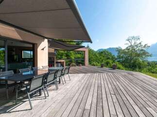 Enjoy outdoor living at its finest with this stunning property featuring a spacious wooden deck and a modern outdoor dining area.
