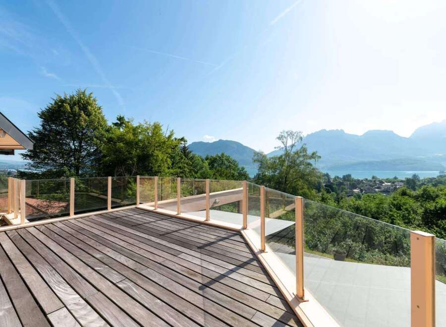 Enjoy breathtaking views from this stunning property! This home features a spacious wooden deck with glass railings, perfect for outdoor relaxation and entertaining.