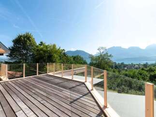 Enjoy breathtaking views from this stunning property! This home features a spacious wooden deck with glass railings, perfect for outdoor relaxation and entertaining.
