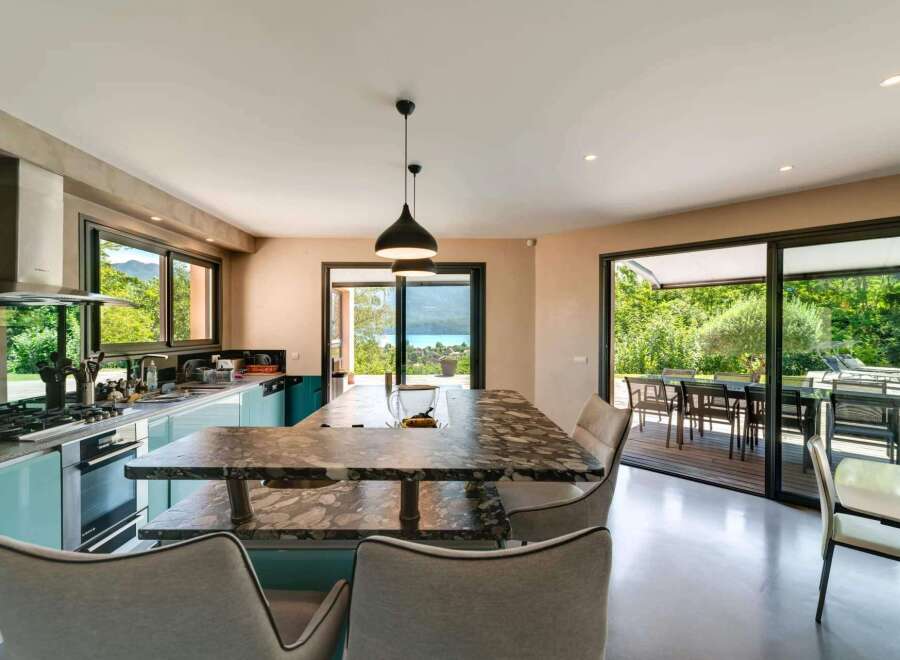 This stunning kitchen boasts a modern design with sleek turquoise cabinetry and a luxurious marble countertop island.