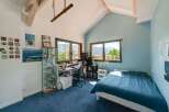 Discover this stunning bedroom with a unique architectural design, featuring exposed wooden beams and a vaulted ceiling.