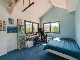 Discover this stunning bedroom with a unique architectural design, featuring exposed wooden beams and a vaulted ceiling.