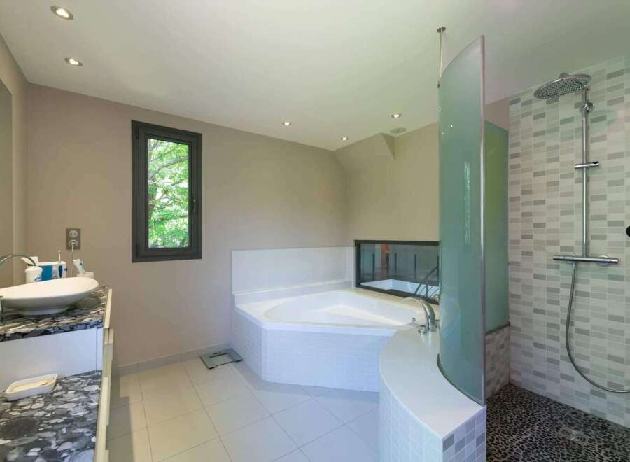 This luxurious bathroom boasts a modern design with a corner bathtub and a separate shower area.