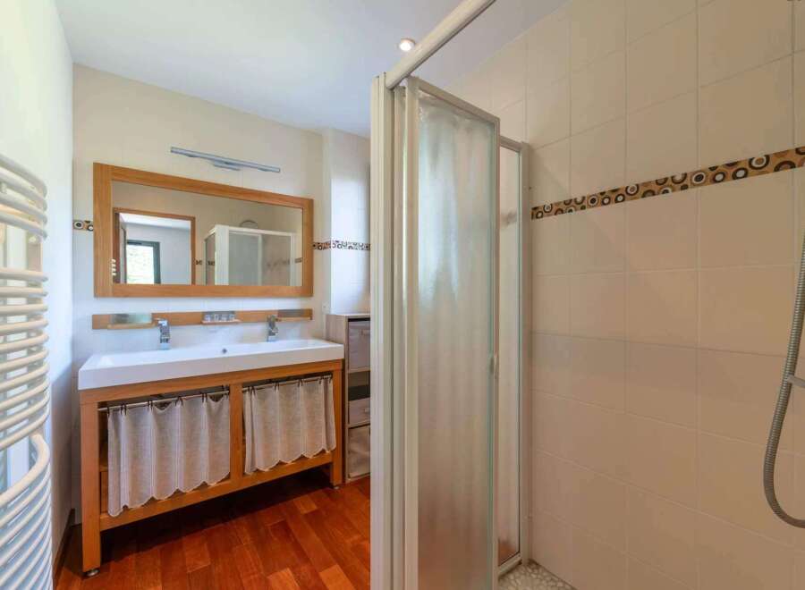 Step into this beautifully designed bathroom, featuring a spacious vanity with a wooden frame and elegant curtains.