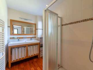 Step into this beautifully designed bathroom, featuring a spacious vanity with a wooden frame and elegant curtains.