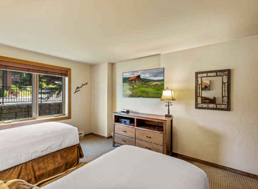 This cozy bedroom features two comfortable beds with crisp white linens and warm brown bed skirts.