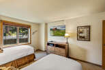 This cozy bedroom features two comfortable beds with crisp white linens and warm brown bed skirts.