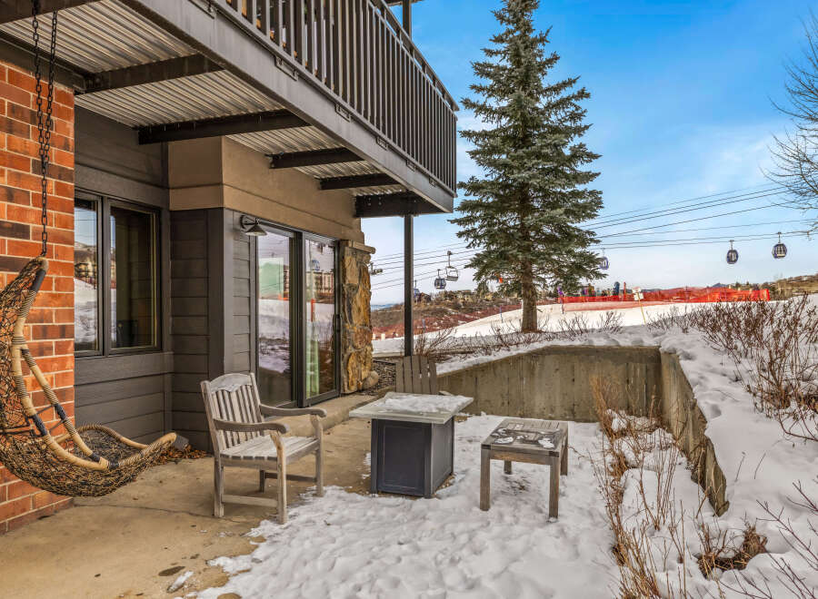 Enjoy the serene beauty of this property with its inviting outdoor seating area, perfect for relaxing in the winter wonderland.