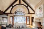 Experience luxury living in this stunning property, featuring a spacious living room with a grand fireplace and a breathtaking view of the snowy landscape.