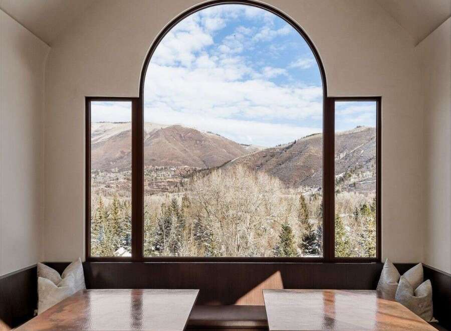 This stunning dining area boasts breathtaking mountain views through a large arched window.