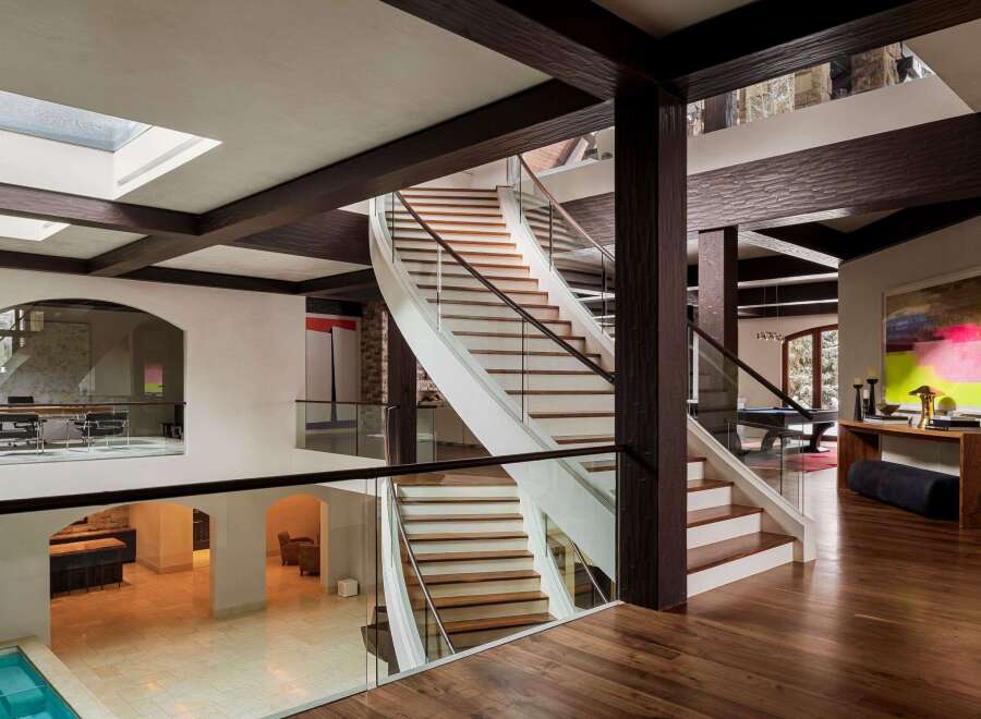 This stunning property boasts a grand staircase with a modern design, complemented by glass railings and wooden steps.