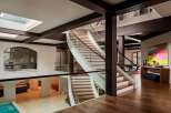This stunning property boasts a grand staircase with a modern design, complemented by glass railings and wooden steps.