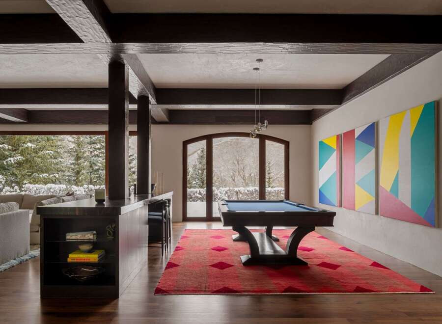 This stunning property features a luxurious game room with a pool table and a vibrant red rug, perfect for entertaining.