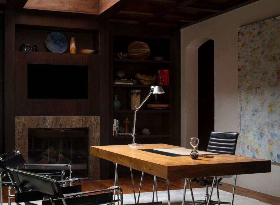 This luxurious home office boasts a sophisticated design with a dark wood ceiling and built-in shelving.