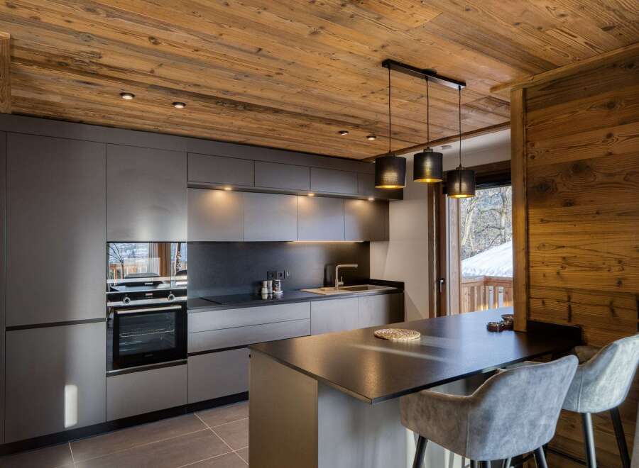 This stunning kitchen boasts a modern design with sleek, gray cabinetry and a contrasting wooden ceiling, creating a warm and inviting atmosphere.