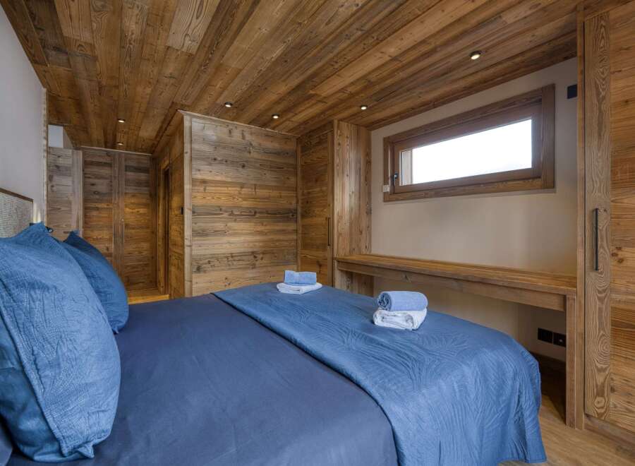 Experience rustic elegance in this stunning bedroom, featuring exquisite wood paneling on the walls and ceiling.