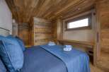 Experience rustic elegance in this stunning bedroom, featuring exquisite wood paneling on the walls and ceiling.