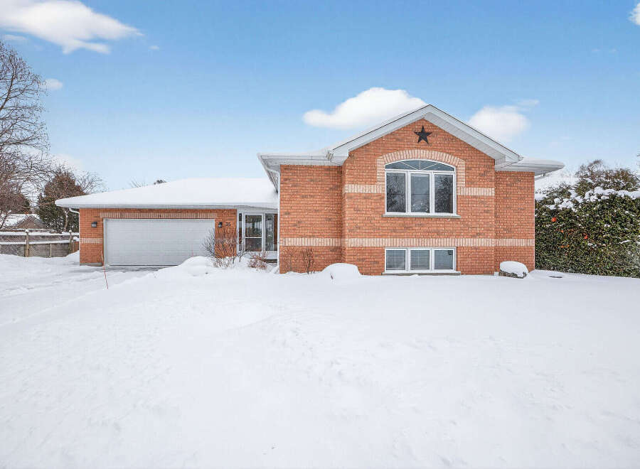 This charming brick home offers a cozy retreat with its inviting facade and snow-covered landscape.