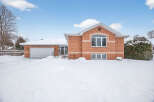 This charming brick home offers a cozy retreat with its inviting facade and snow-covered landscape.
