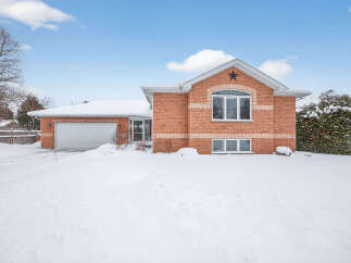 This charming brick home offers a cozy retreat with its inviting facade and snow-covered landscape.