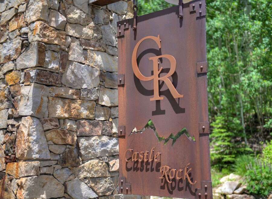 Discover the charm of Castle Rock with this stunning property! This home boasts a beautiful stone facade and a welcoming entrance sign.