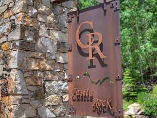 Discover the charm of Castle Rock with this stunning property! This home boasts a beautiful stone facade and a welcoming entrance sign.